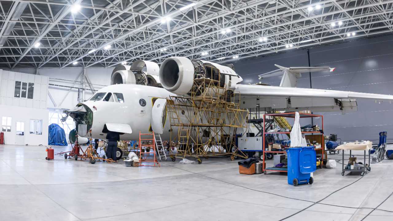 AS9100 vs ISO 9100 guide - plane in hanger undergoing maintenance inspection